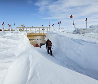 Nathan Chellman walking into the research trench over drifted snow.